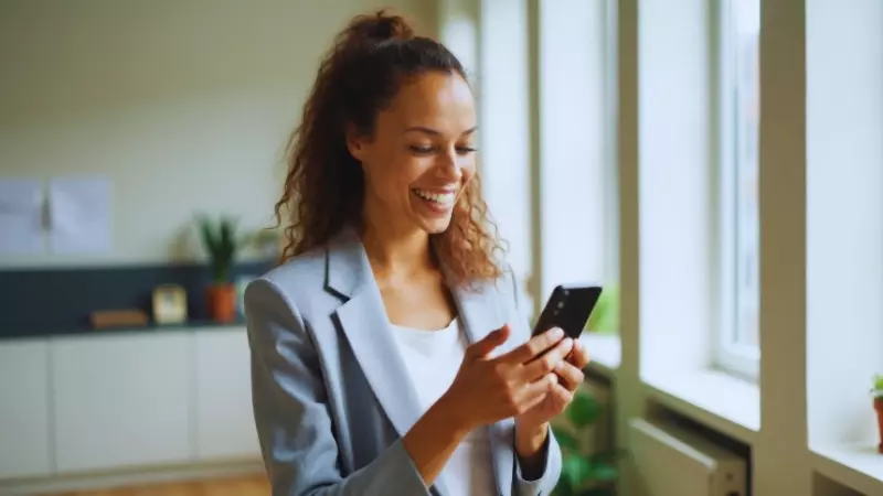 Mulher representando revendedora sorrindo enquanto utiliza o celular para divulgar produtos nas redes sociais, representando estratégias de marketing digital para aumentar as vendas.